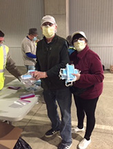photo of lion Bill and PCC Nanette Burdick packaging masks to be given out.